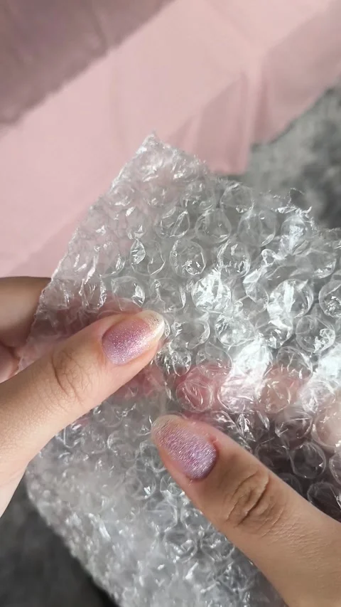 Woman bursts bubbles on a packaging bubble wrap, trying to calm down. Burst the Stock Footage 314974645