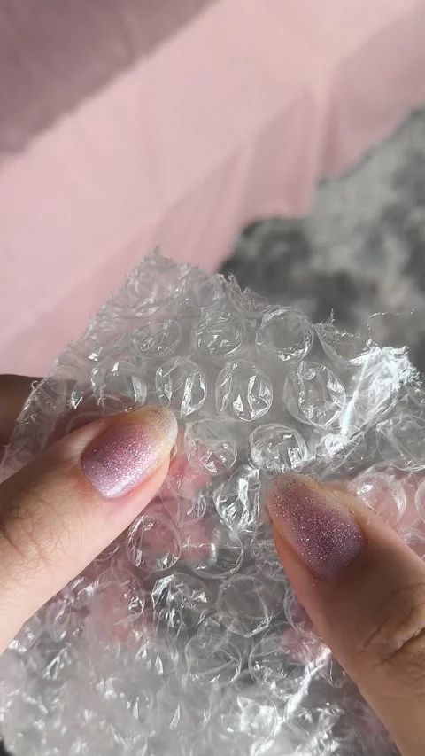 Woman bursts bubbles on a packaging bubble wrap, trying to calm down. Burst the Stock-Footage 314974682