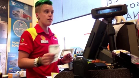 Woman buying lottery ticket and tapping credit card at check out counter Stock Footage