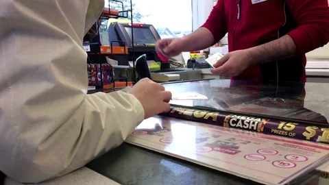 Woman buying scratch tickets at check out counter Stock Footage