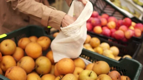 Woman buys fruits in a supermarket, yellow beautiful apples. She puts the bags Stock Footage 118896849