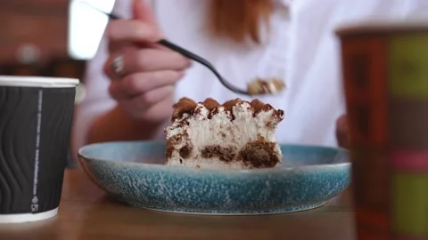 A woman in a cafe drinks coffee, eats a delicious dessert at the table Stock Footage 155729637