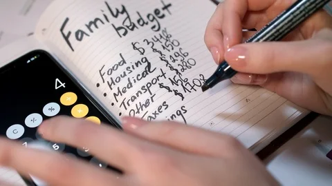 Woman calculate family budget on calculator and writing in notebook Stock Footage