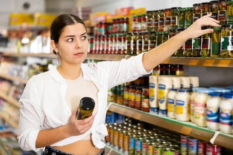 Woman came to canned vegetables department. Girl chooses jar of canned Stock Photos