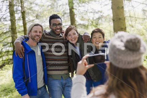 Woman with camera phone photographing friends hiking in woods Stock Photos