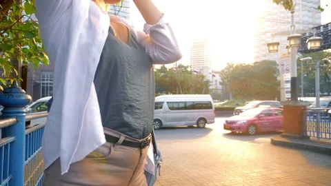 A woman with a camera walks through the streets of a large modern city Stock Footage 101336940