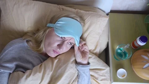 A woman cannot fall asleep and wants to drink a capsule with melatonin, a sleepi Stock Footage 287705246