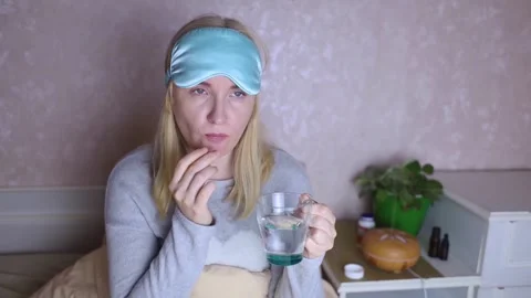 A woman cannot fall asleep and wants to drink a capsule with melatonin, a sleepi Stock Footage 287705269