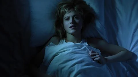 Woman cannot take comfortable position in cheap bed of hotel room, sleeplessness Stock Photos