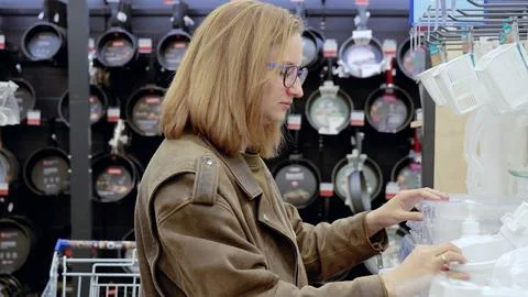 Woman carefully selecting plastic kitchenware in supermarket houseware Stock Photos