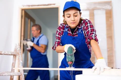Woman carpenter using jigsaw in construction site Foto stock