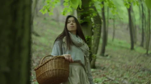 Woman carries a wicker basket through the serene forest woods Stock Footage 320041653