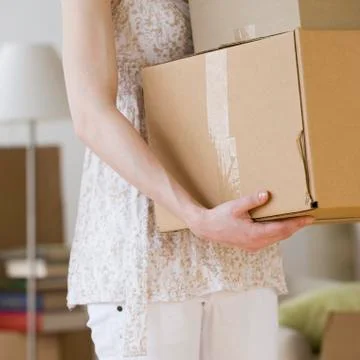 Woman carrying stack of moving boxes Stock Photos