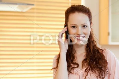 Woman with cellphone in the kitchen Stock Photos