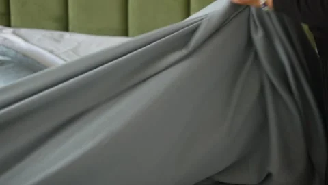 Woman changes bed linen by removing old gray sheet from bed in slow motion,.. Stock Footage 333153159