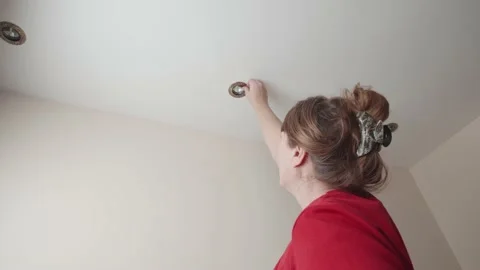 Woman changing or checking a ceiling light bulb in her home. Stock-Footage 144089791