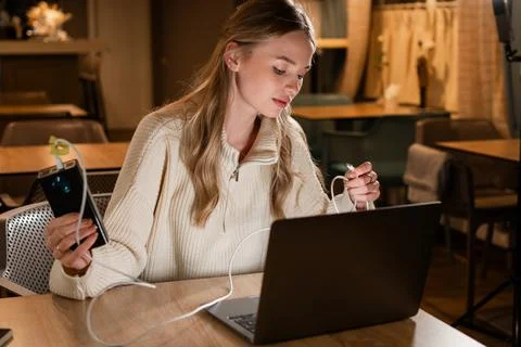 Woman charging devices while working on laptop Stock Photos