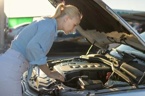 Woman checking car engine after breakdown, performing vehicle inspection wh.. Stock Photos