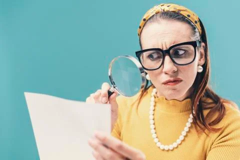 Woman checking carefully a document using a magnifier 写真素材