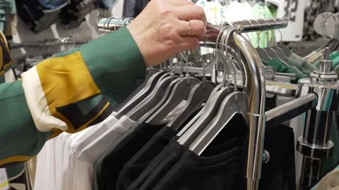 Woman checking clothes on hangers while looking for size Stock Footage 336997716