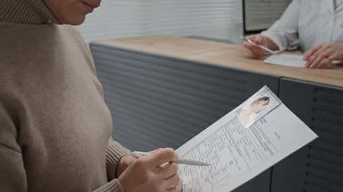 Woman Checking Data in Medical Document and Turning to Hospital Receptionist Stock Footage 332664964