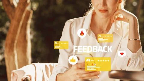 Woman checking feedback on a smartphone while seated outdoors in a casual Stock Photos