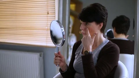Woman checking her appearance in the mirror and telling beautician what she want Stock Footage 76029410