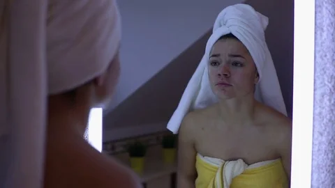 Woman checking her face in the mirror in bathroom  Stock Footage 69916996