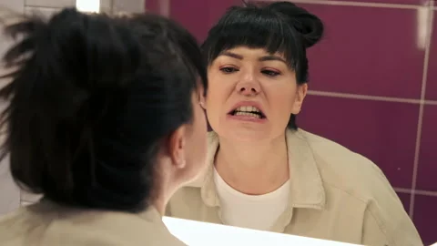 Woman checking her teeth in mirror with opened mouth looking Vídeo Stock 168362292