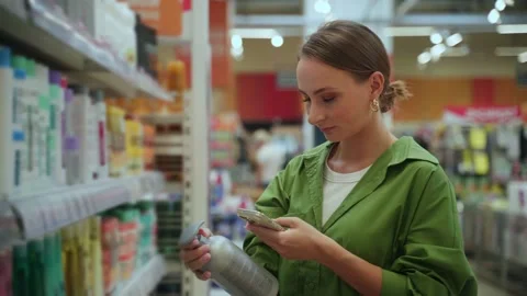 Woman checking product information using smartphone in supermarket Stock Footage 285027904