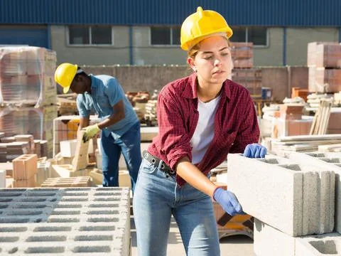 Woman checking quality of bricks at construction store Stock Photos