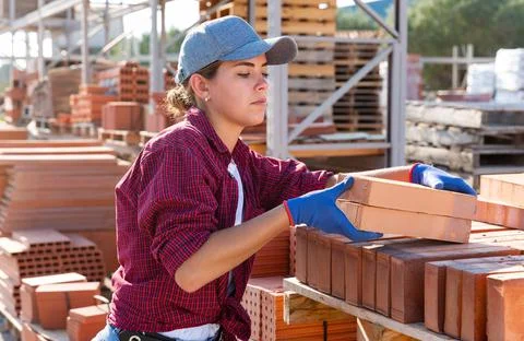 Woman checking quality of bricks at construction store 스톡 사진