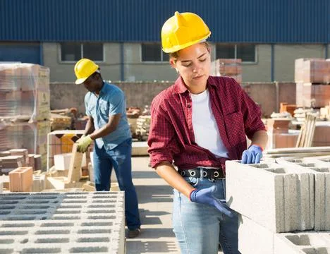 Woman checking quality of bricks at construction store Foto stock