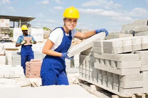 Woman checking quality of bricks at construction store 스톡 사진