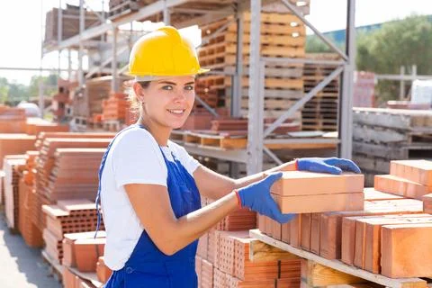 Woman checking quality of bricks at construction store 스톡 사진