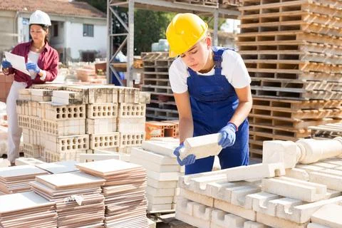 Woman checking quality of bricks at construction store Stock Photos