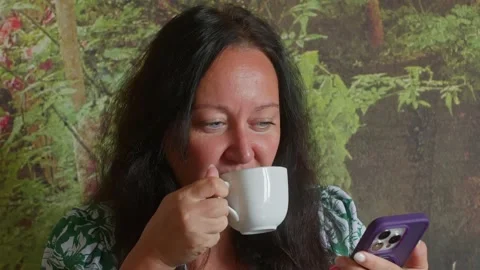 Woman checking smartphone while holding coffee cup morning routine Video stock 344516832