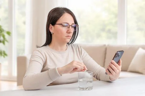 Woman checking smartphone while taking medication, concept of health tracki.. Foto stock