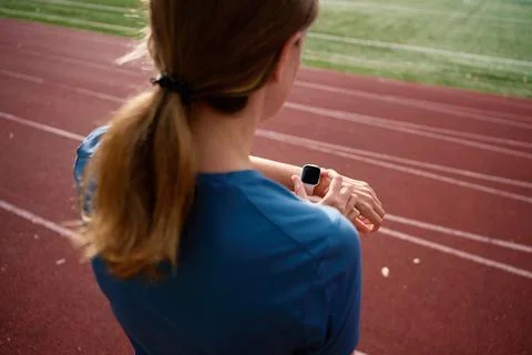 Woman checking smartwatch during workout on running track Stock Photos