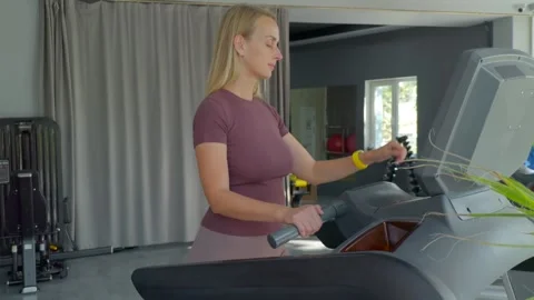 Woman checking smartwatch while walking on treadmill in modern gym Stock Footage 318585580