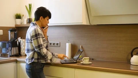 Woman checking something on laptop while speaking with someone on cellphone Stock Footage 73309180