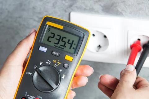 Woman checking voltage in power socket Foto stock