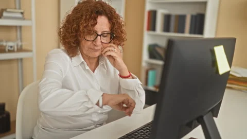 Woman checking watch, typing at computer and holding hand to ear at a desk .. Stock Footage 347698268