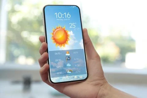 Woman checking weather using app on smartphone indoors, closeup. Data, sun .. Foto stock