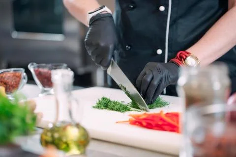 A Woman Chef cuts vegetables in the kitchen in a restaurant. Stock Photos