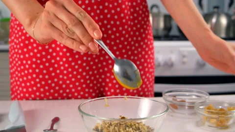 Woman chef hands cooking adding honey to bowl of mixed walnuts with spoon. Stock Footage 312999003