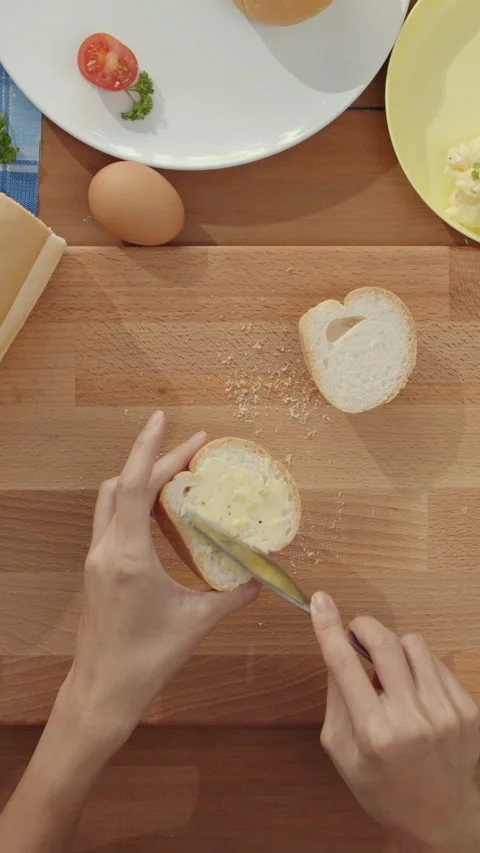 Woman chef spread butter on rustic rye bread with metal knife on wooden board. Stock-Footage 335991184