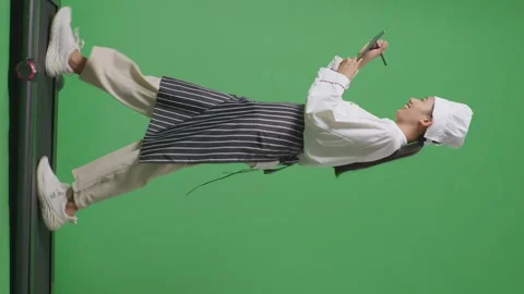 Woman Chef Taking Note On A Tablet While Walking On Treadmill On Green Screen Stock Footage 249622859