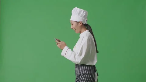 Woman Chef Walking And Using Smartphone In The Green Screen Background Studio Stock Footage 249623101