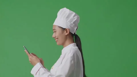 Woman Chef Walking And Using Smartphone In The Green Screen Background Studio Stock Footage 249623294